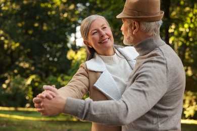 Photo of Affectionate senior couple dancing together in park. Romantic date