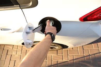 Photo of Man inserting plug into electric car socket at charging station, above view