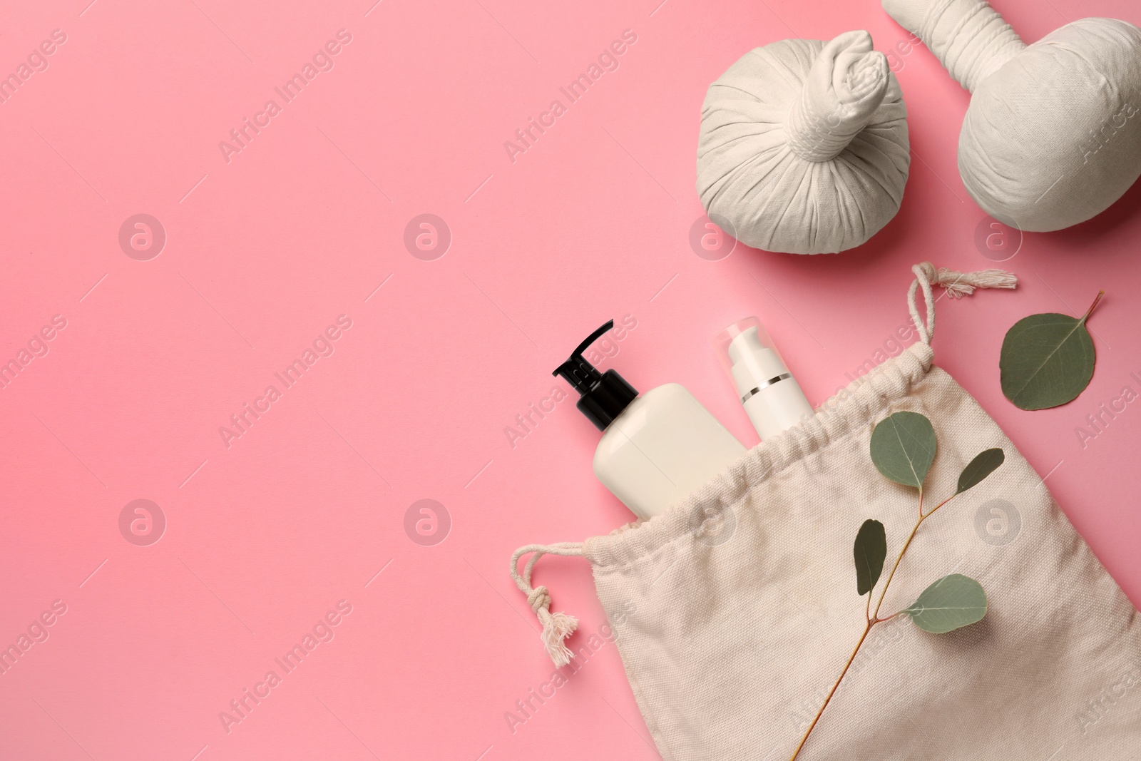 Photo of Preparation for spa. Compact toiletry bag with different cosmetic products, herbal bags and eucalyptus on pink background, flat lay. Space for text