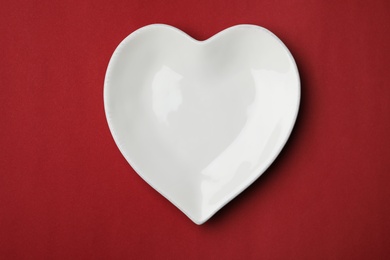 Heart shaped plate on color background, top view