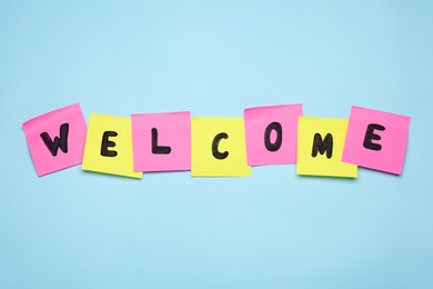 Word Welcome made of paper notes on light blue background, top view