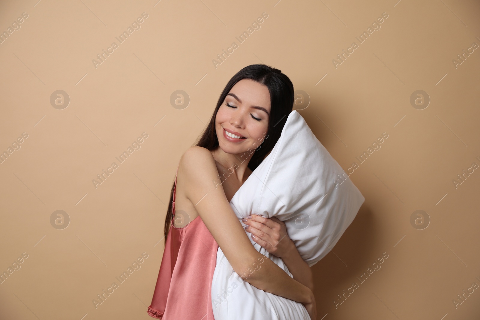 Photo of Beautiful Asian woman with pillow on beige background. Bedtime