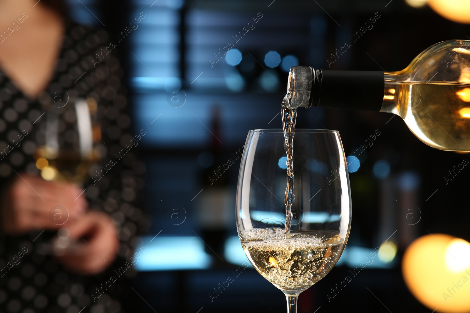 Photo of Pouring white wine from bottle into glass in bar, closeup. Space for text