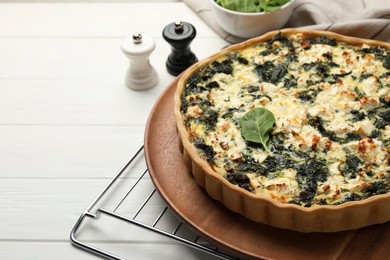 Photo of Delicious homemade spinach quiche on white wooden table, closeup. Space for text