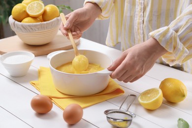 Photo of Woman cooking lemon curd at white wooden table, closeup