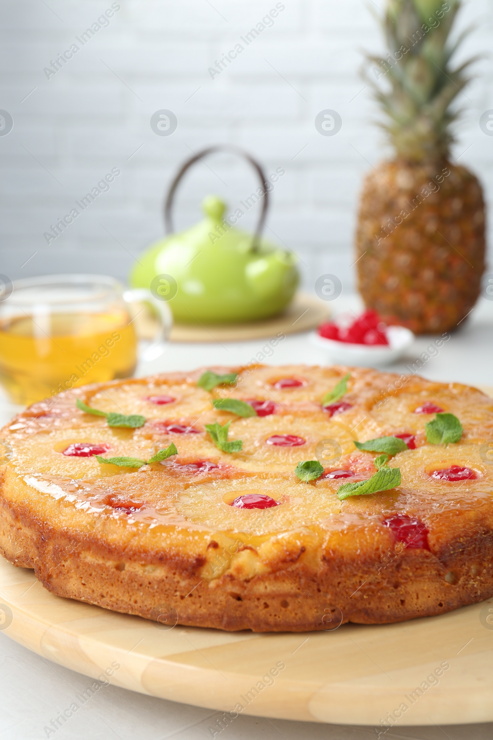 Photo of Tasty pineapple cake with cherries and mint on white table. Space for text