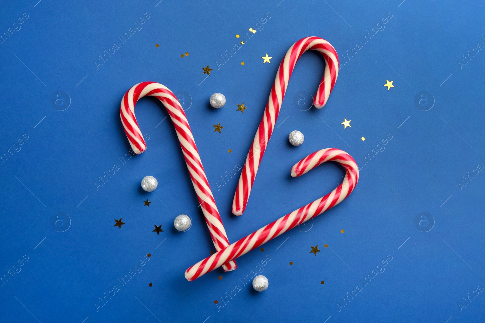 Photo of Candy canes on blue background, flat lay. Christmas treat