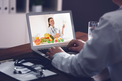 Doctor using laptop for online consultation with nutritionist via video chat, closeup