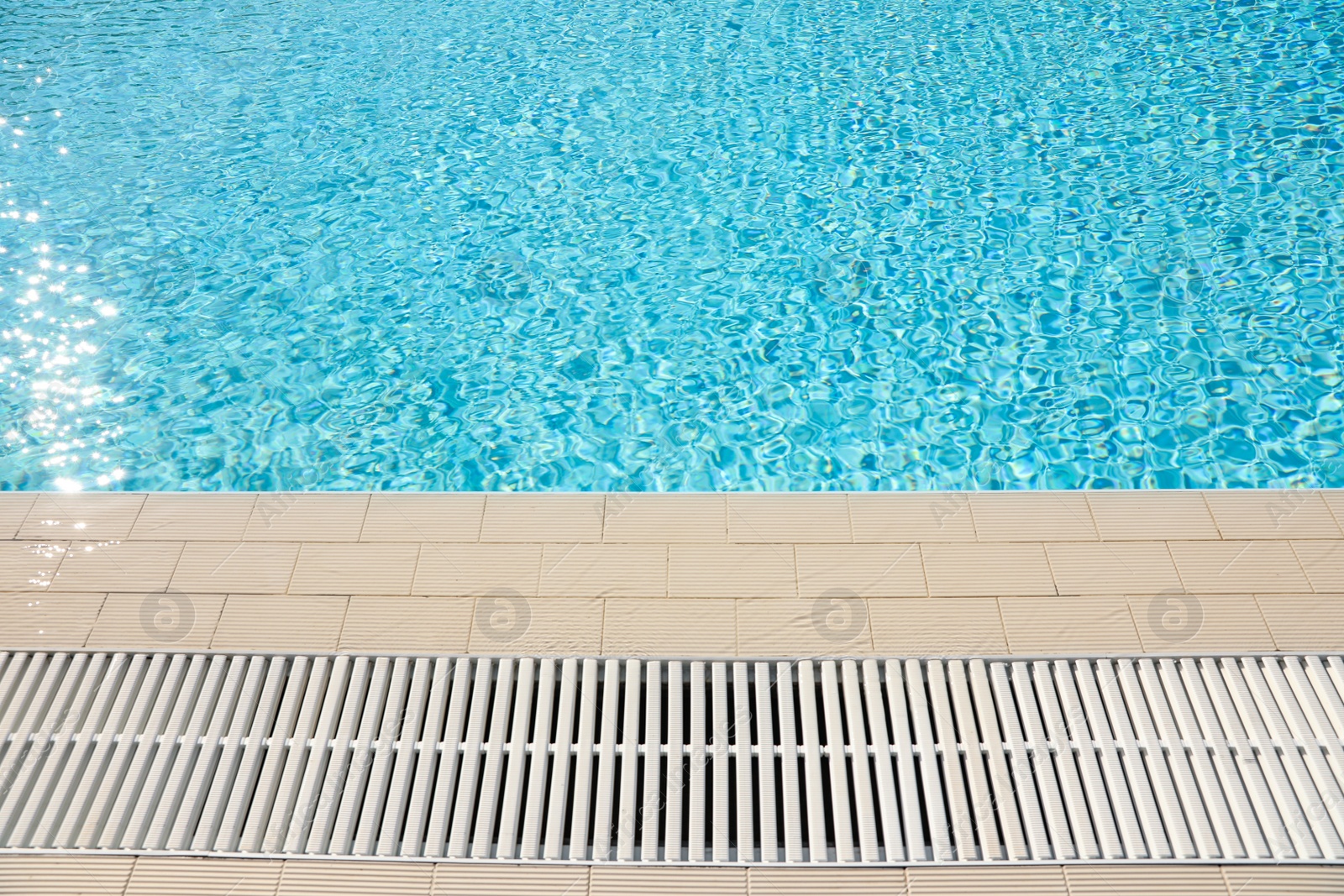 Photo of Edge of swimming pool with clear water on sunny day. Summer vacation