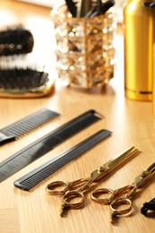 Photo of Hairdresser tools. Different scissors and combs on wooden table, closeup