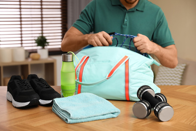 Photo of Man packing sports bag for training indoors, closeup