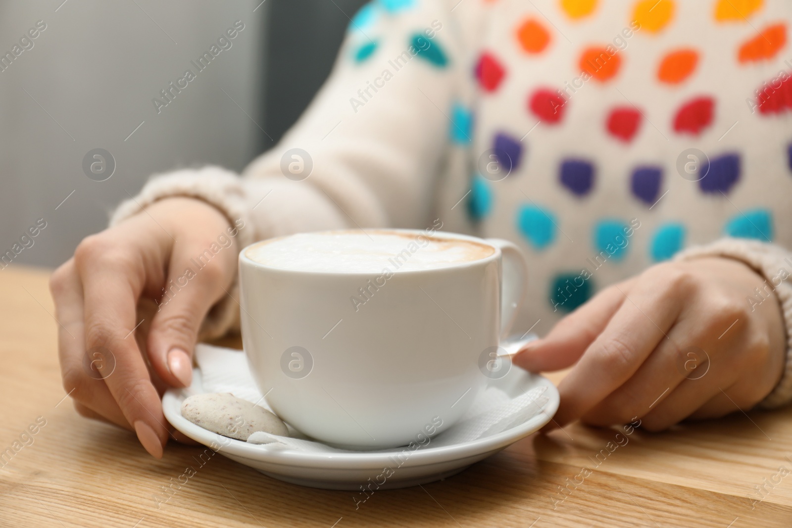 Photo of Woman with cup of aromatic cacao at table, closeup