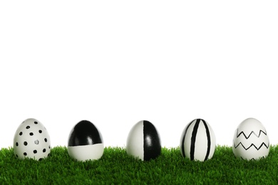 Photo of Line of painted Easter eggs on green lawn against white background