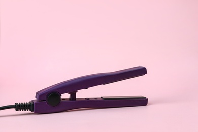 Photo of Modern hair iron for straightening on color background