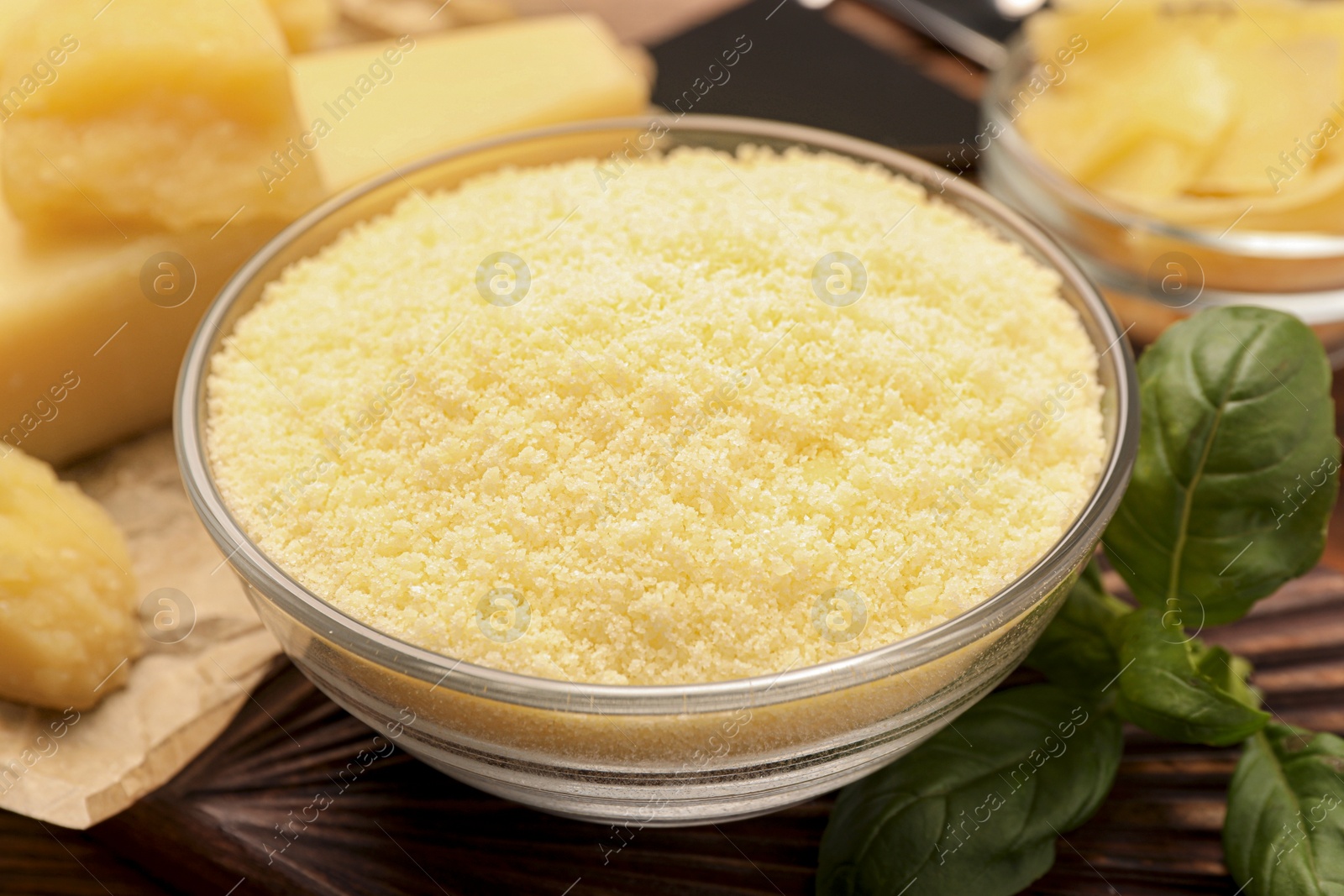 Photo of Delicious grated parmesan cheese in bowl on wooden table, closeup