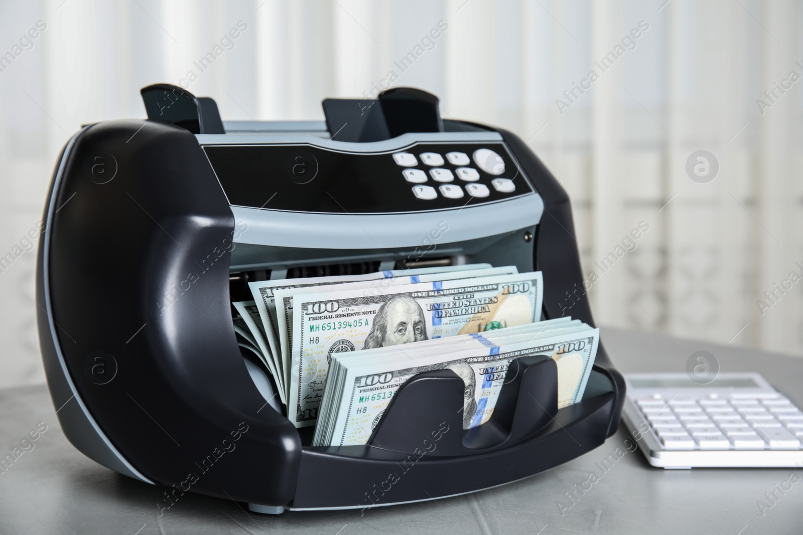 Photo of Modern electronic bill counter with money on table indoors