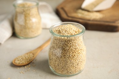 Jar with white quinoa on light grey table