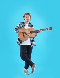 Young man playing acoustic guitar on color background