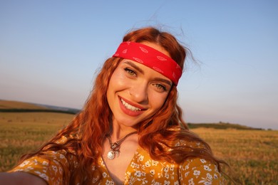 Beautiful happy hippie woman taking selfie in field