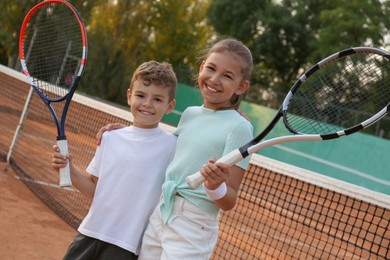 Happy children with tennis rackets on court outdoors