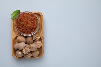 Nutmeg powder, seeds and green leaf on white background, top view. Space for text
