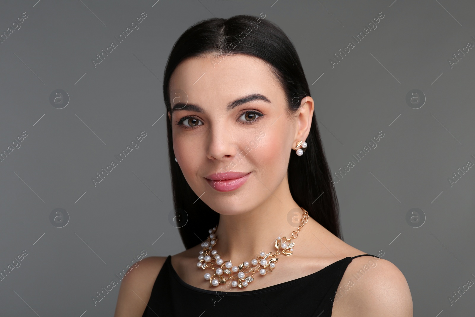 Photo of Beautiful young woman with elegant jewelry on dark grey background