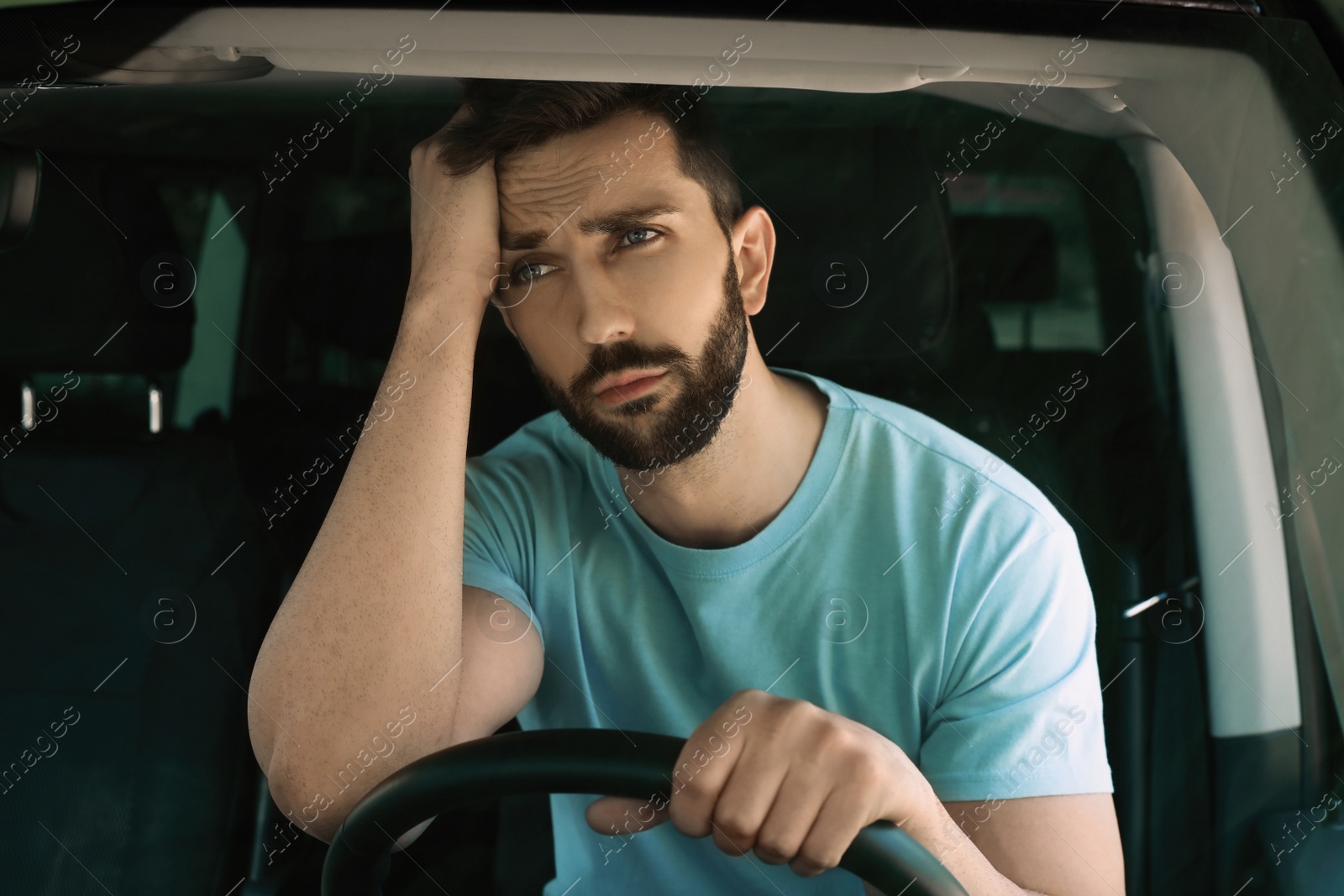 Photo of Stressed man in driver's seat of modern car, view through windshield