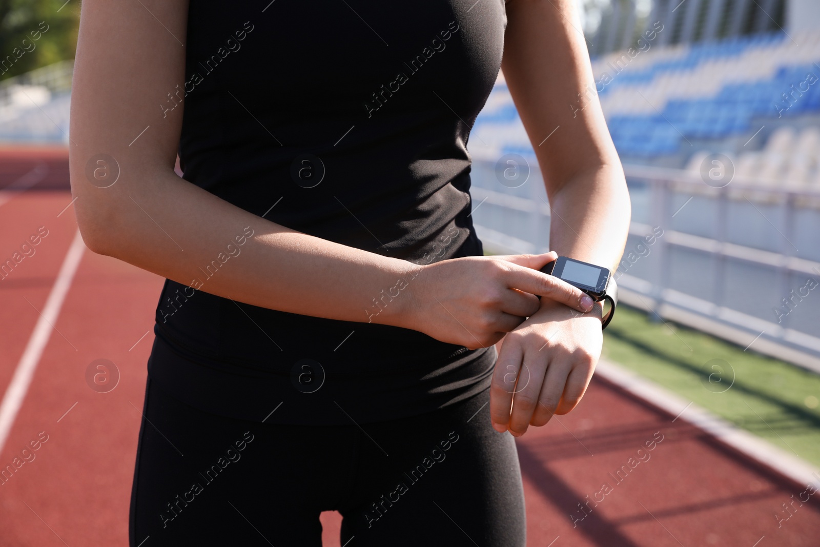 Photo of Woman checking fitness tracker after training at stadium, closeup