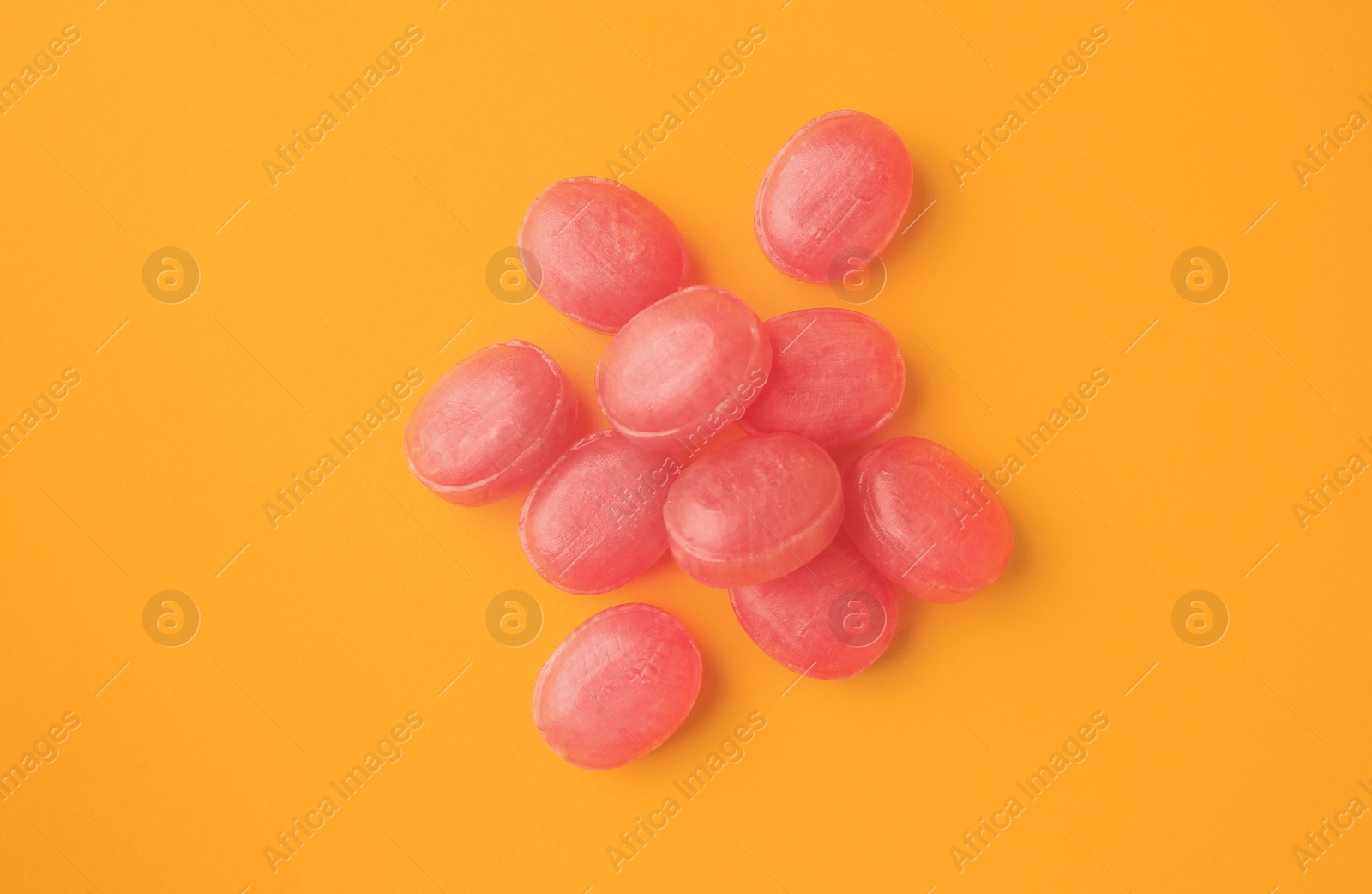 Photo of Many pink cough drops on orange background, flat lay