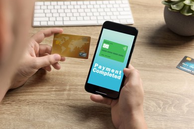 Image of Man successfully made payment using online banking application on smartphone at wooden table, closeup