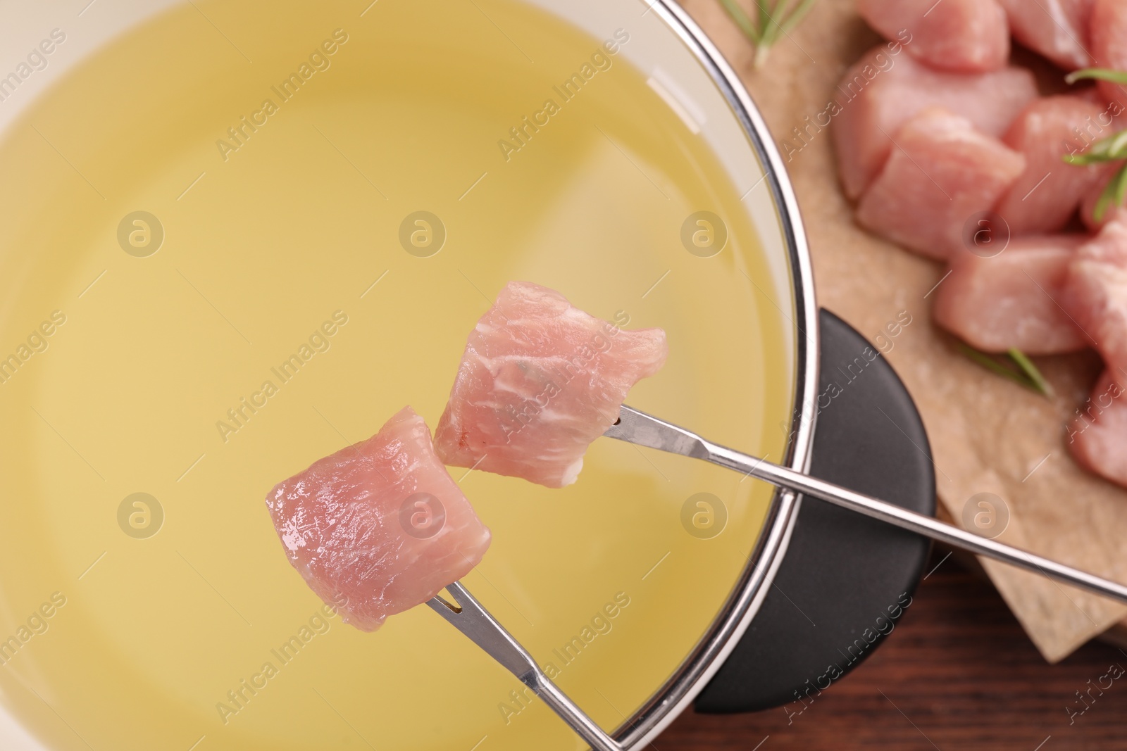 Photo of Forks with pieces of raw meat and fondue pot, top view