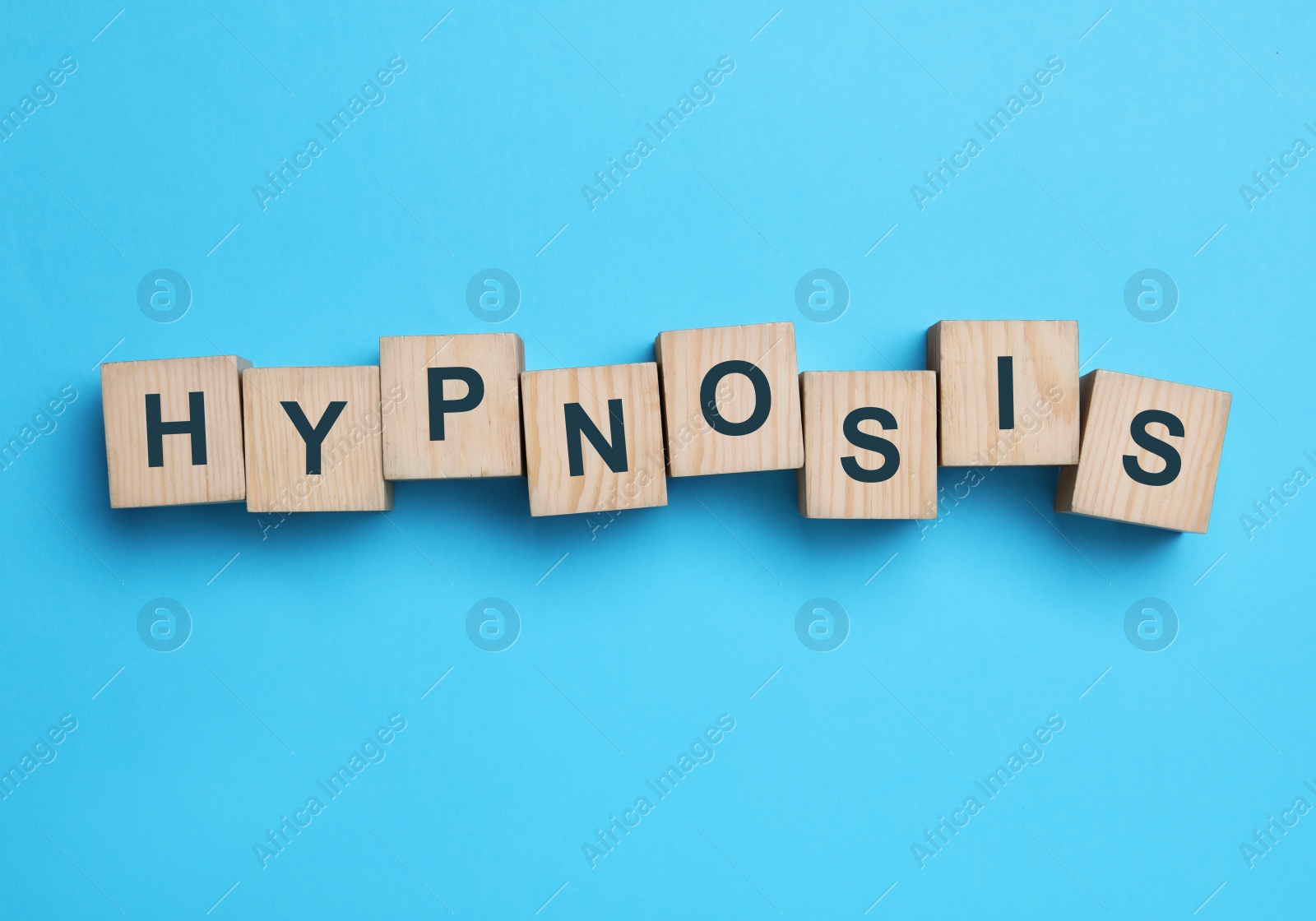 Photo of Wooden blocks with word HYPNOSIS on light blue background, flat lay