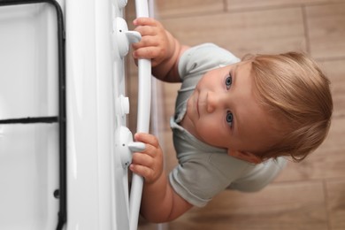 Little child playing with gas stove indoors, above view. Dangers in kitchen