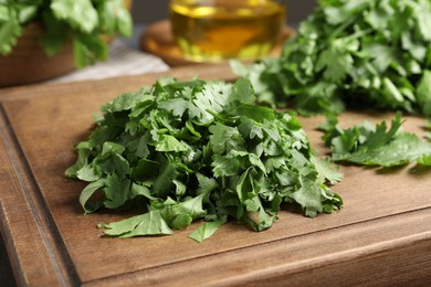 Photo of Cut fresh green cilantro on wooden board, closeup