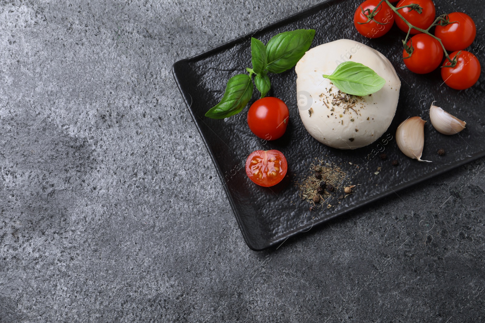 Photo of Delicious mozzarella with tomatoes and basil leaves on light gray textured table, top view. Space for text