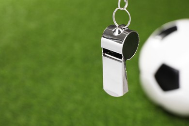 Photo of Football referee equipment. Metal whistle and soccer ball on green grass, closeup with space for text