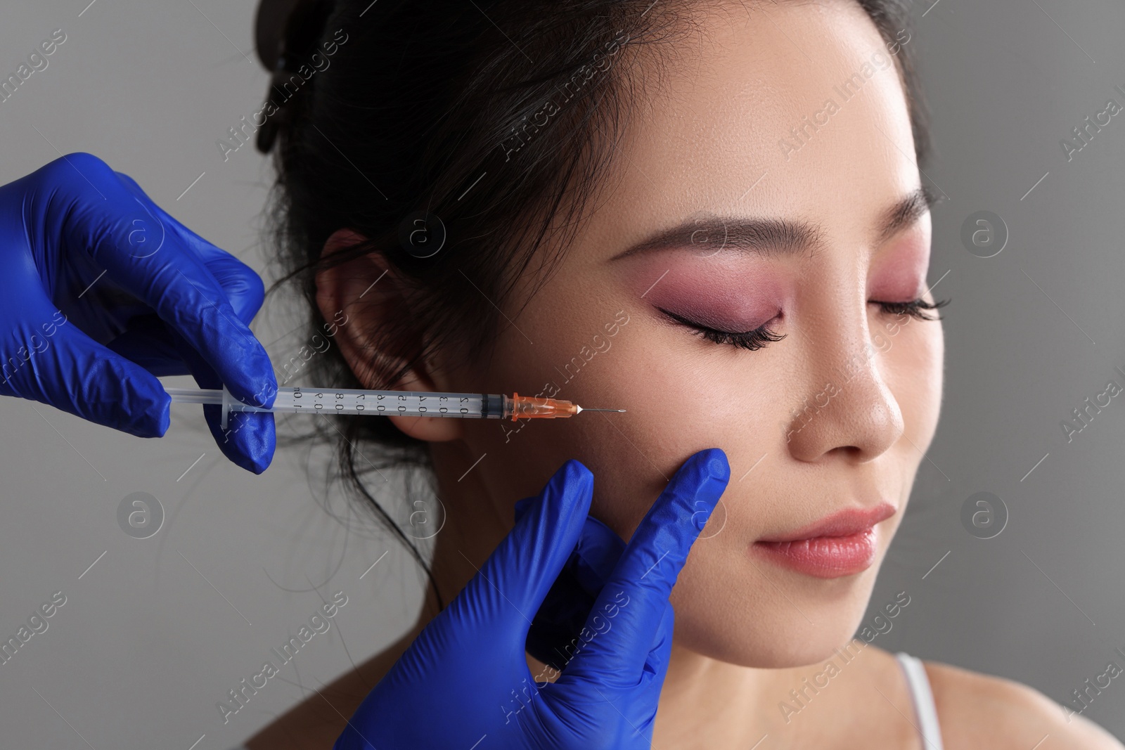 Photo of Woman getting facial injection on grey background, closeup