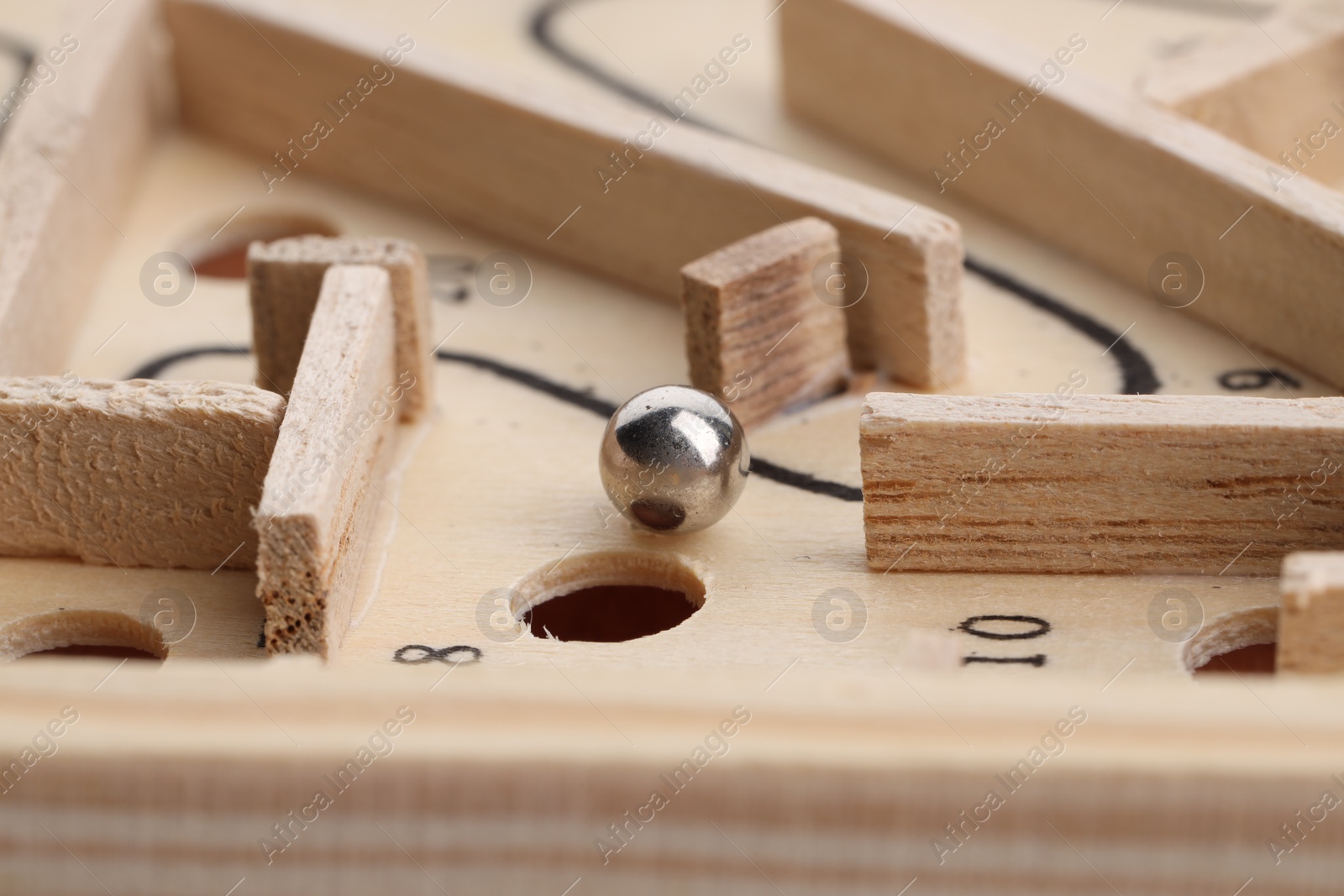 Photo of Wooden toy maze with metal ball, closeup