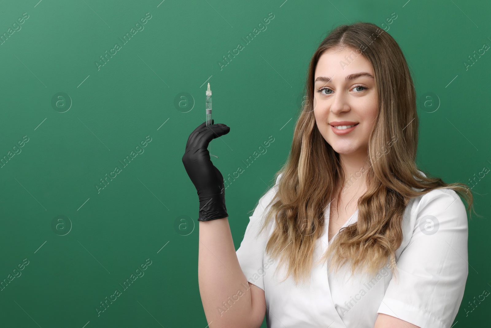 Photo of Portrait of cosmetologist with syringe on green background, space for text