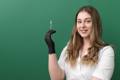 Portrait of cosmetologist with syringe on green background, space for text