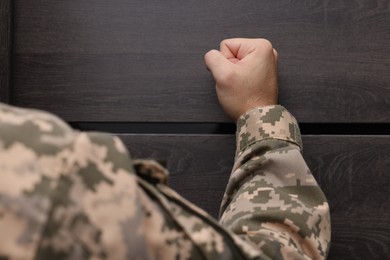 Photo of Military commissariat representative knocking on wooden door, closeup