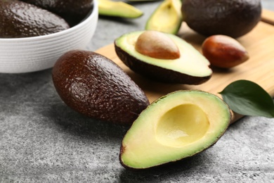 Photo of Whole and cut avocados on grey table, closeup
