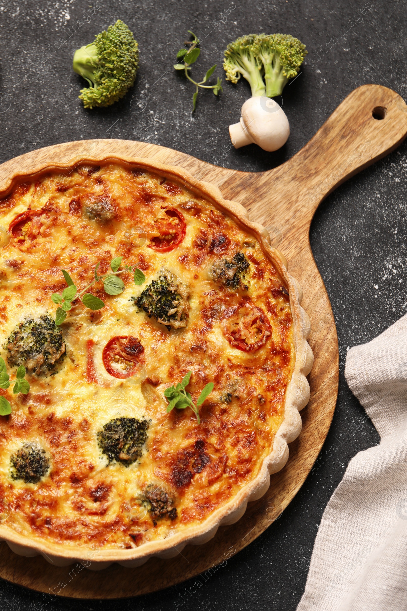 Photo of Delicious homemade vegetable quiche, oregano, broccoli and mushroom on black table, flat lay