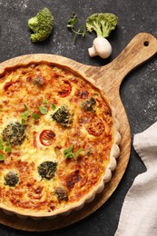 Delicious homemade vegetable quiche, oregano, broccoli and mushroom on black table, flat lay