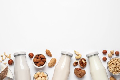 Photo of Vegan milk and different nuts on white background, flat lay. Space for text