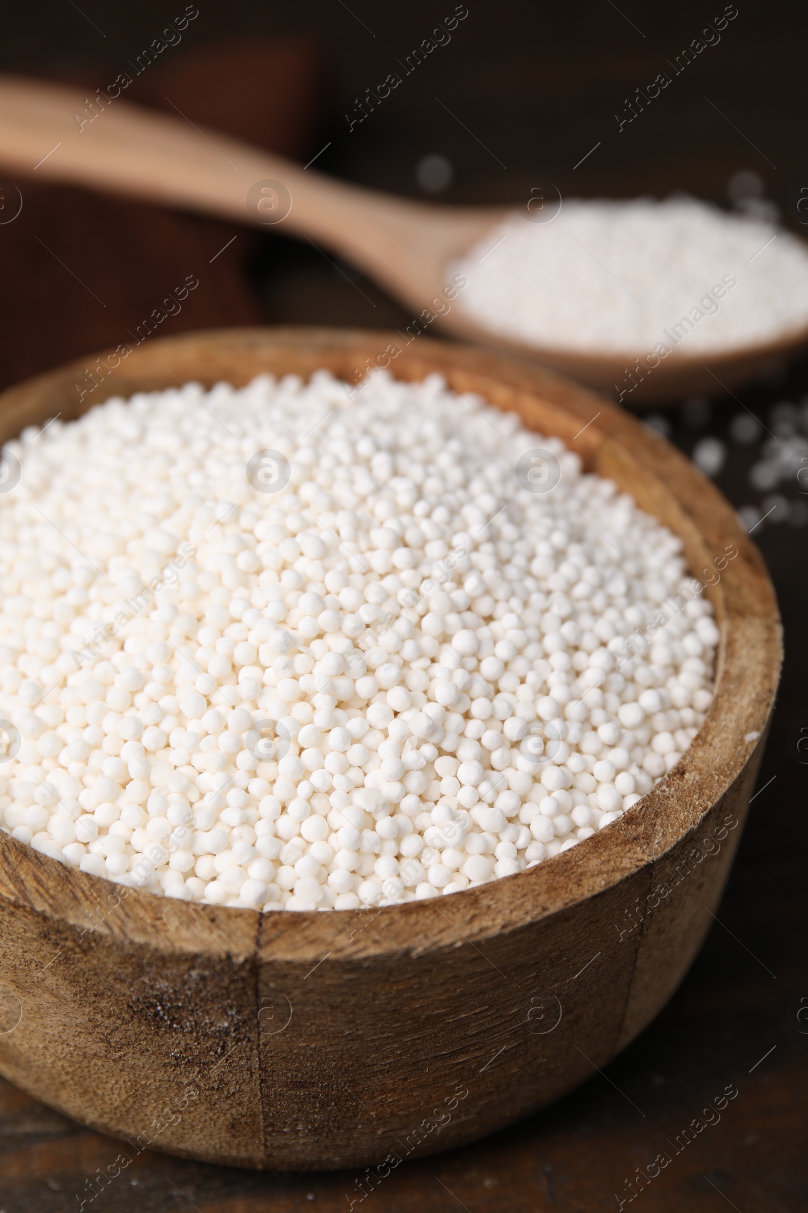 Photo of Tapioca pearls in bowl on wooden table, closeup