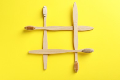 Bamboo toothbrushes on yellow background, top view