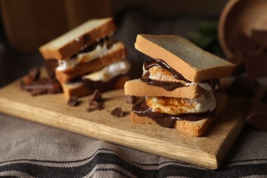 Delicious marshmallow sandwiches with bread and chocolate on wooden board, closeup
