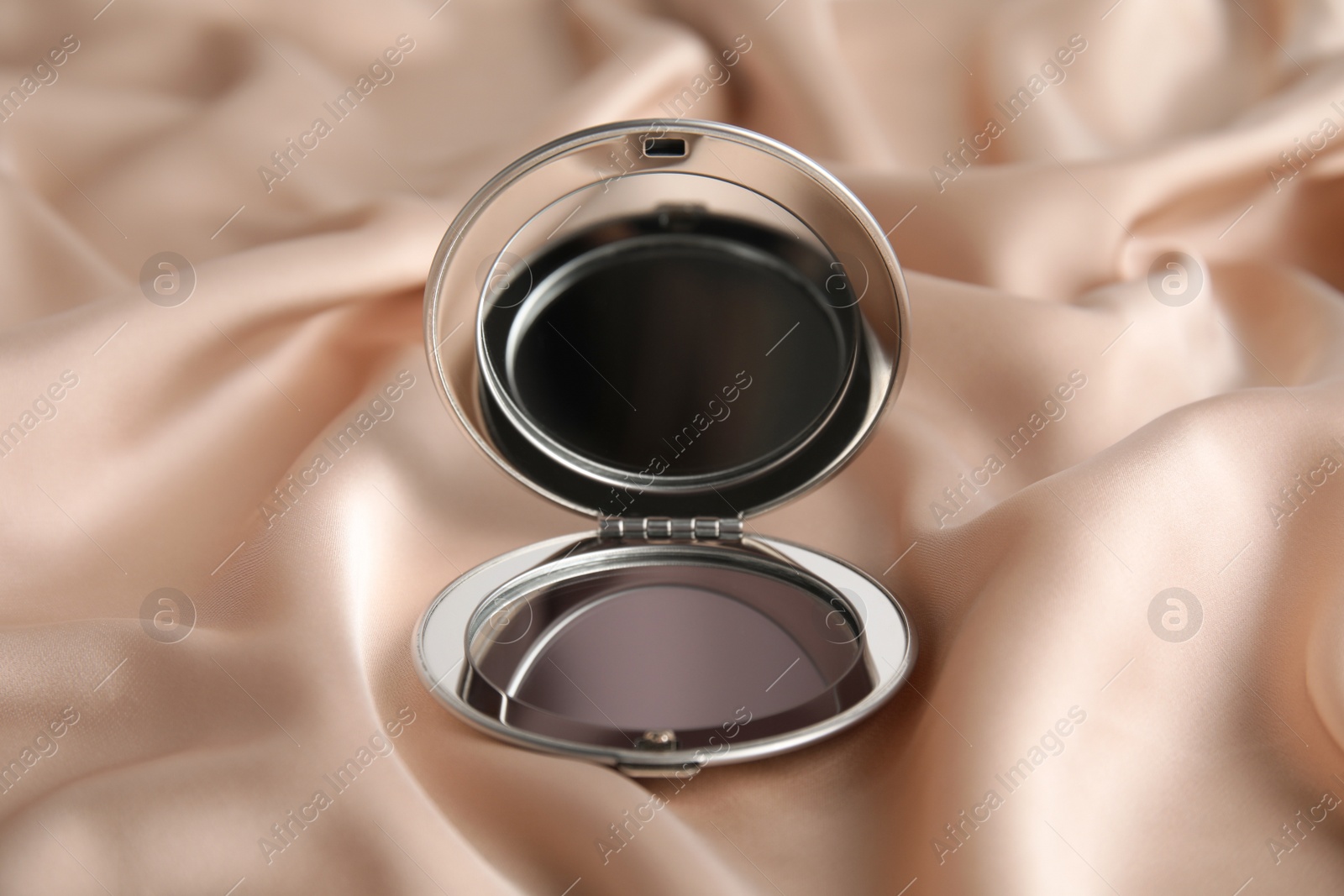 Photo of Silver cosmetic pocket mirror on rose gold fabric