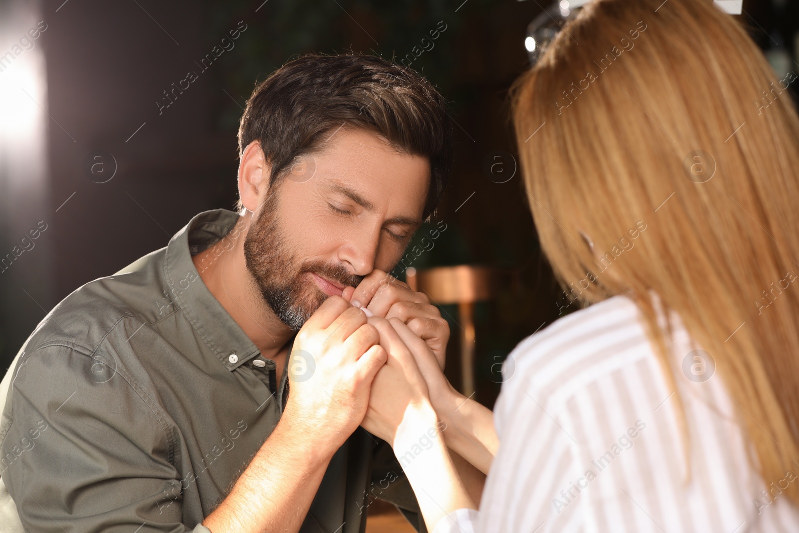 Photo of Romantic date. Lovely couple holding hands together indoors